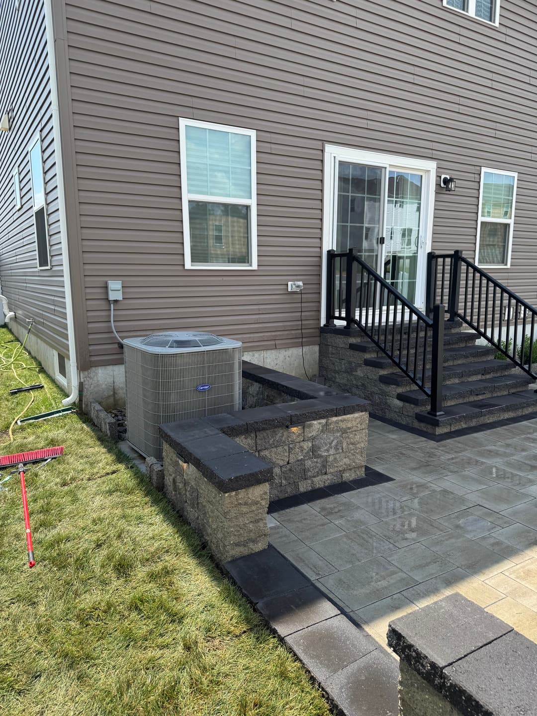 Backyard view featuring air conditioning unit, stone steps, and patio next to a modern house.