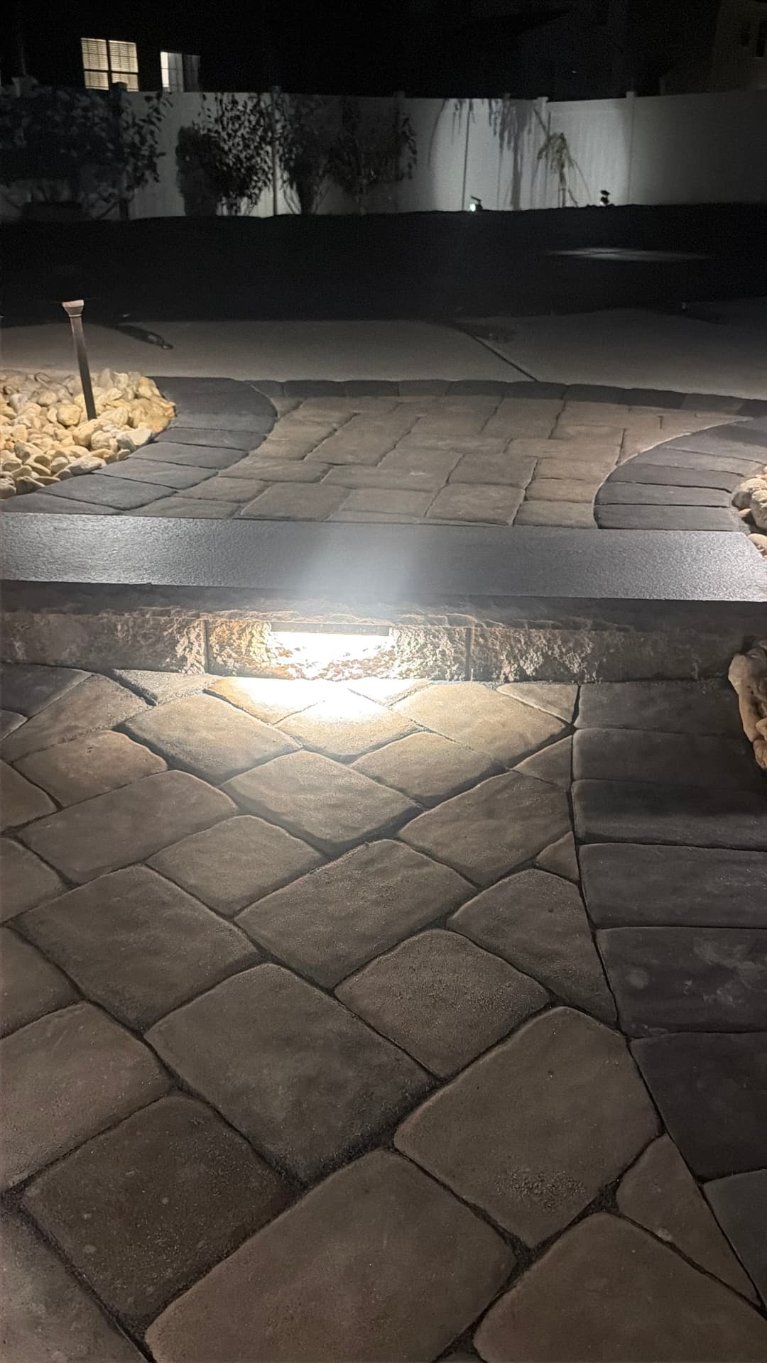 Illuminated stone pathway at night with decorative rocks and soft lighting accents.