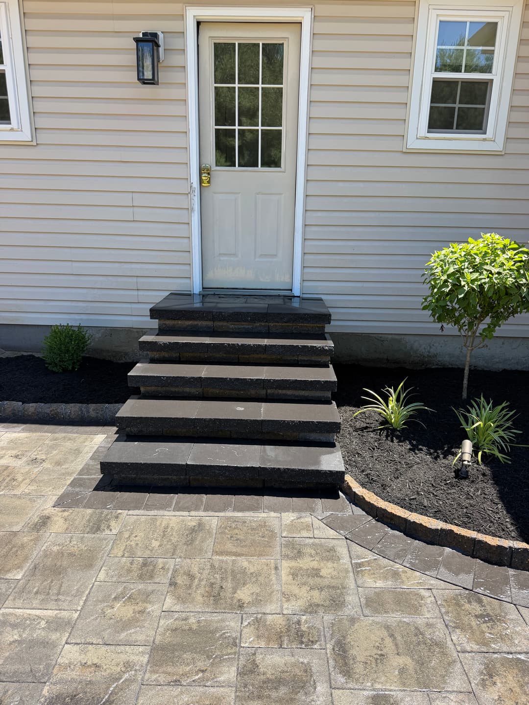 Front entrance with concrete steps, door, and landscaped garden area.