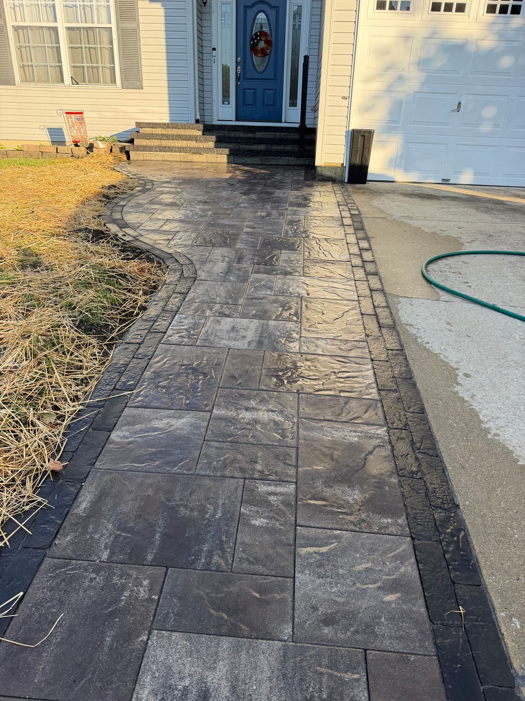 Stylish paver walkway leading to a blue front door with seasonal decoration.