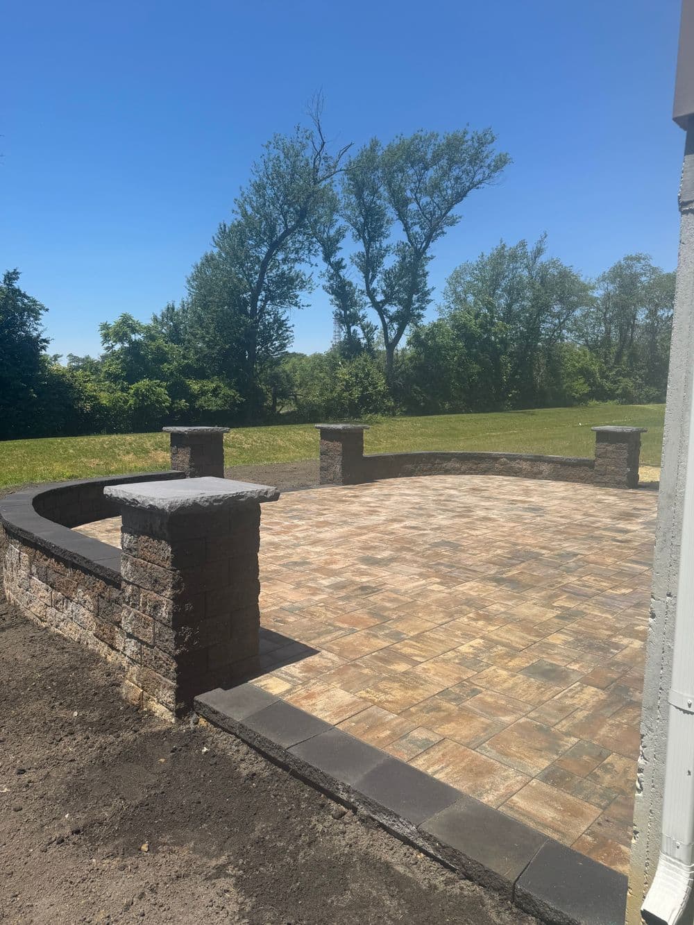 Paved outdoor patio with stone pillars and green landscape in the background.