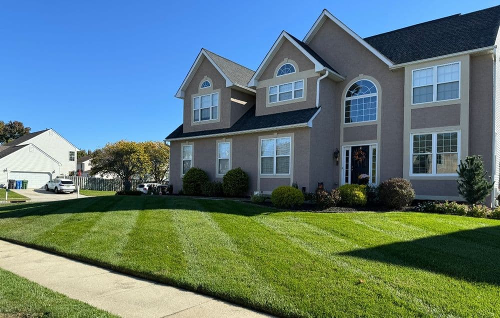 Beautiful two-story home with manicured lawn and clear blue sky. Ideal suburban neighborhood setting.