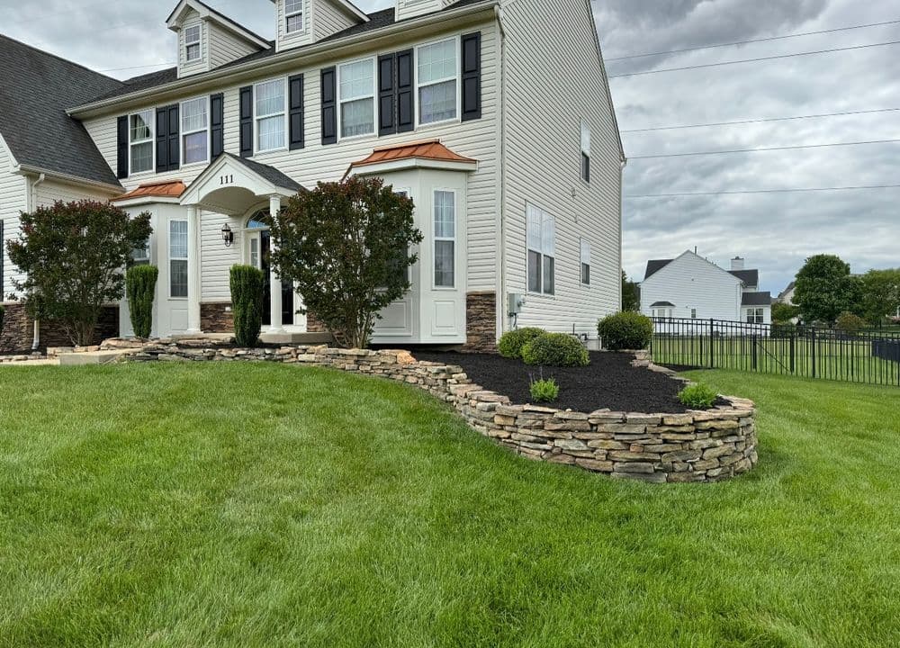 Front view of a modern home with landscaped yard and stone retaining wall.