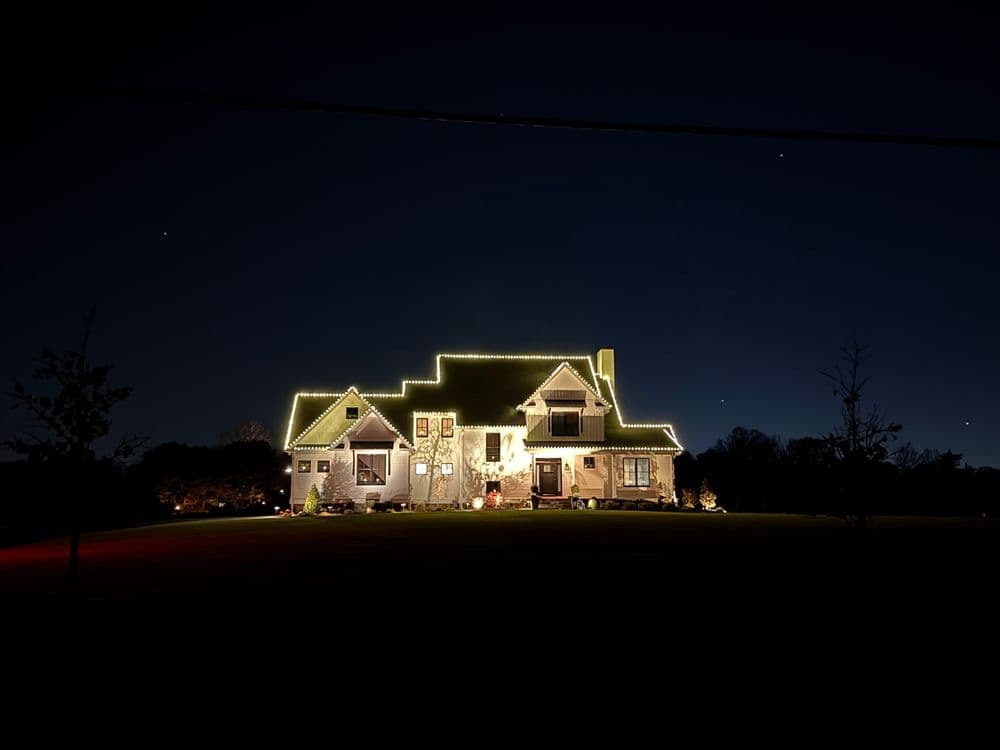 House decorated with festive lights at night, showcasing a charming holiday spirit.