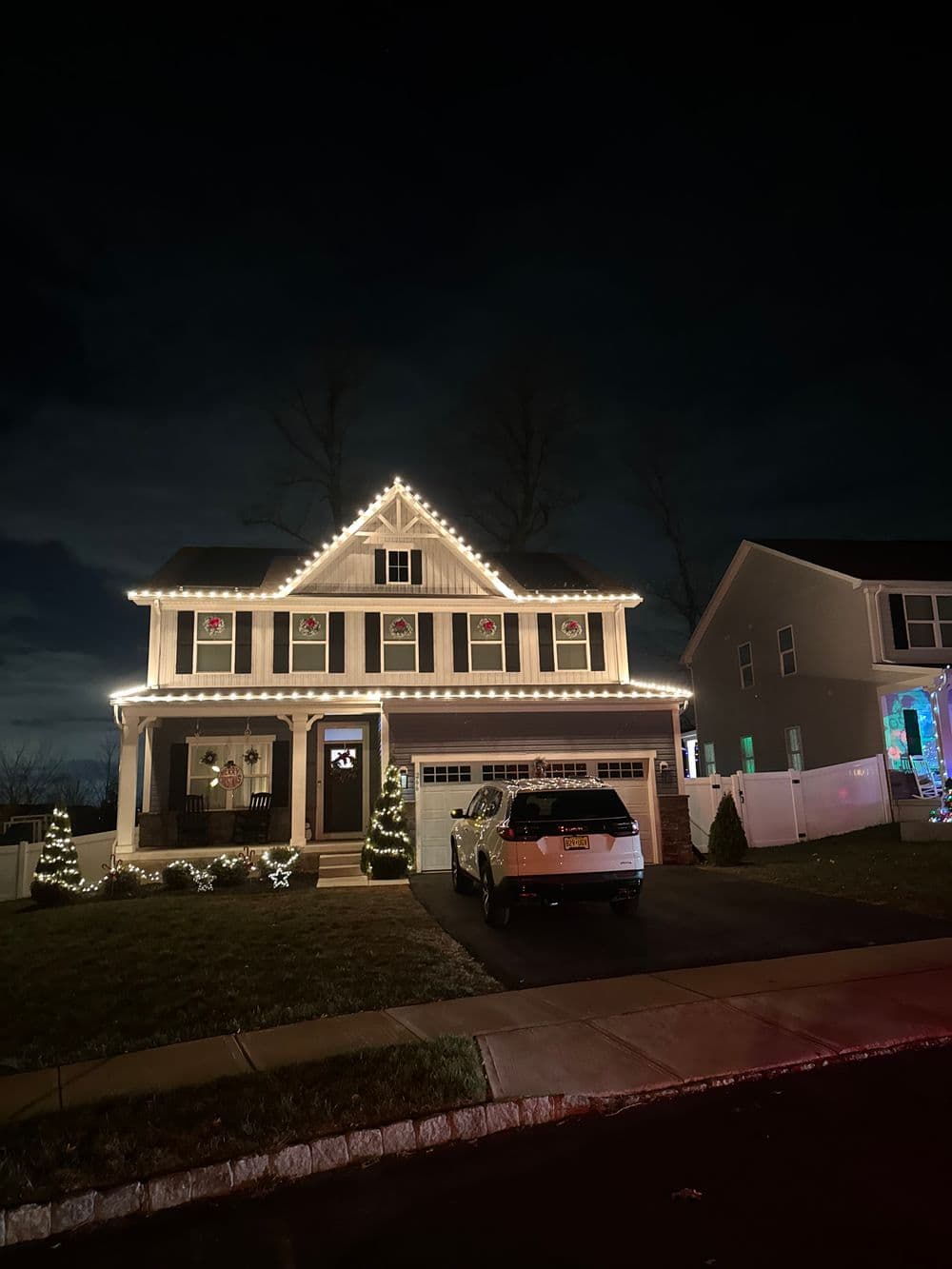 Christmas lights illuminate a charming house at night, creating a festive holiday atmosphere.