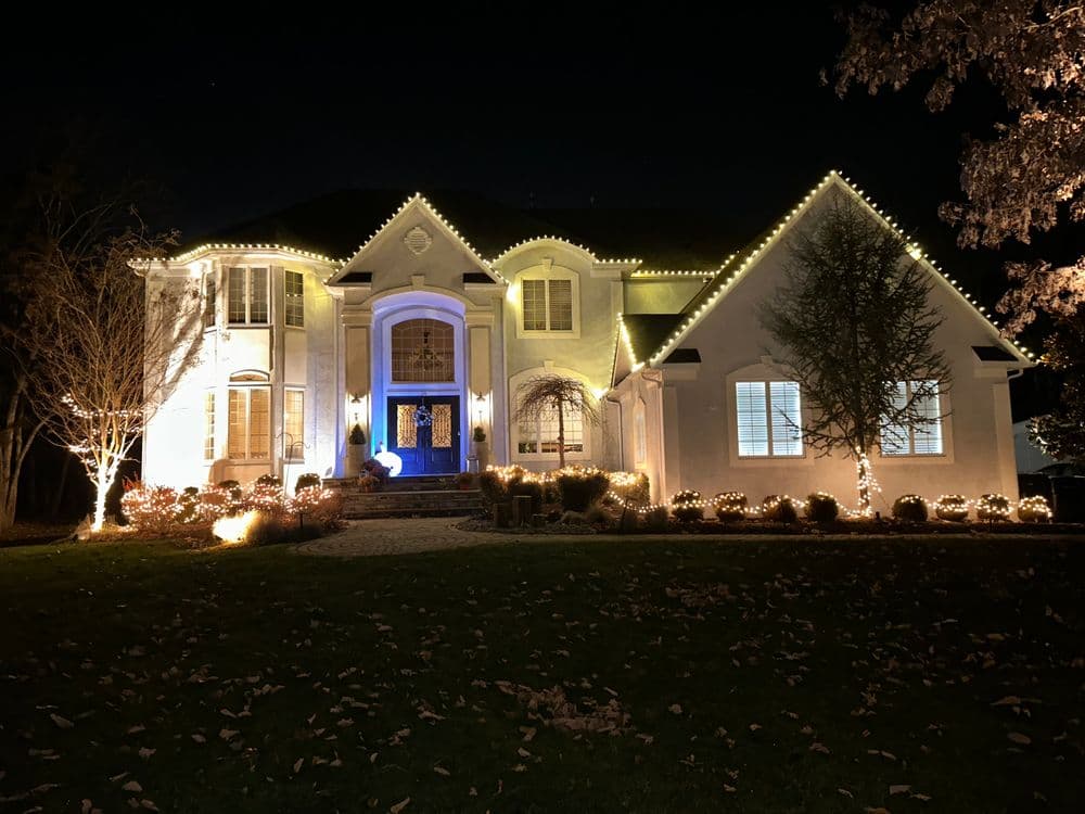 Elegant house decorated with festive lights at night, showcasing blue and white illumination.