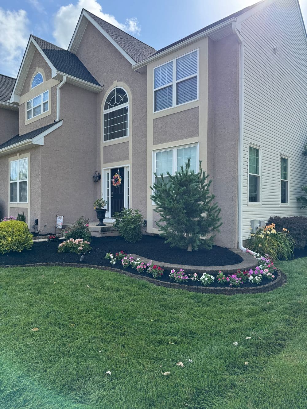 Charming house with well-maintained landscaping, flower beds, and grassy lawn.