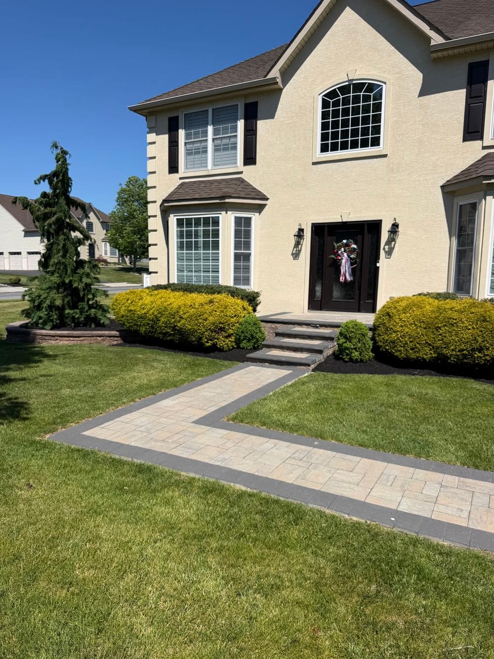 Elegant home exterior with landscaped yard, stone pathway, and decorative front entrance.